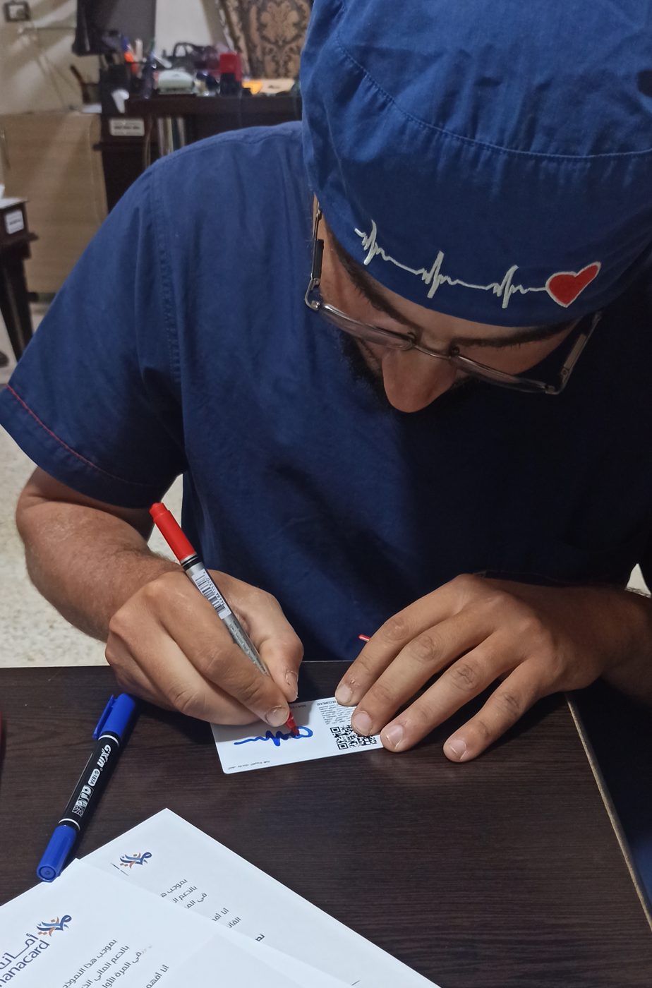 A health worker signs his new Amanacard beside the enrolment form